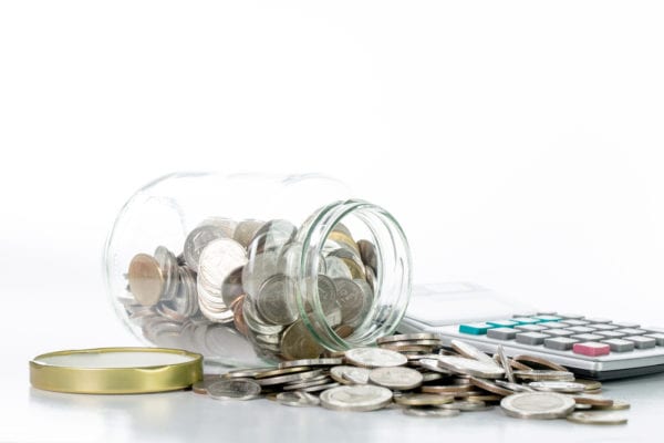 Coins spilling onto a table with a calculator, demonstrating total cost of ownership (TCO) of a CMMS