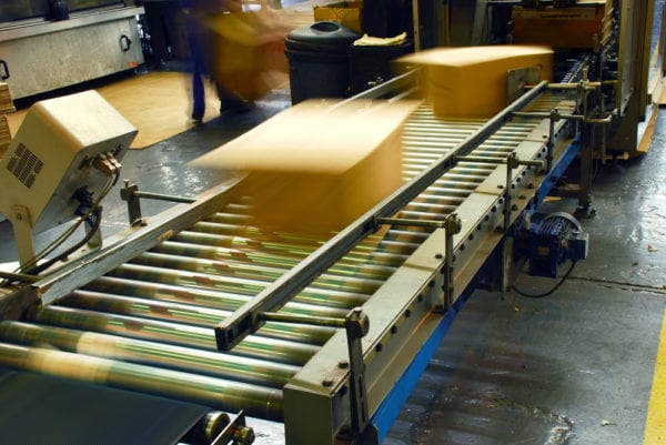 Boxes on a conveyor belt moving quickly, demonstrating an increase in production due to competition