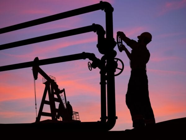 A technician closes the valve on the tube of an oil pump as a regulatory compliance task in a CMMS.