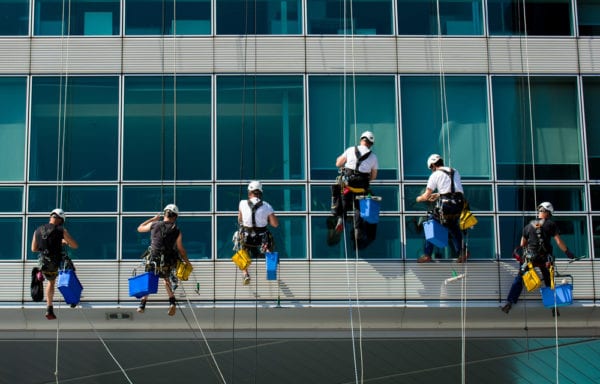 Climbing window washers cleaning the outside of an office building as part of facility-centric corrective maintenance