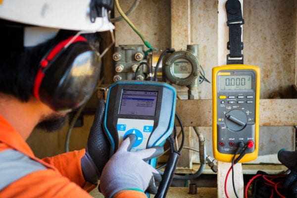 A technician performing a preventive maintenance calibration test on a pneumatic control valve with a specialized instrument.