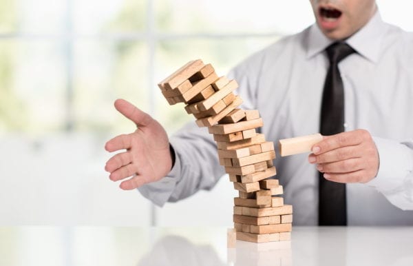 Businessman topples a tower of blocks, representing the concept of CMMS implementation failure 