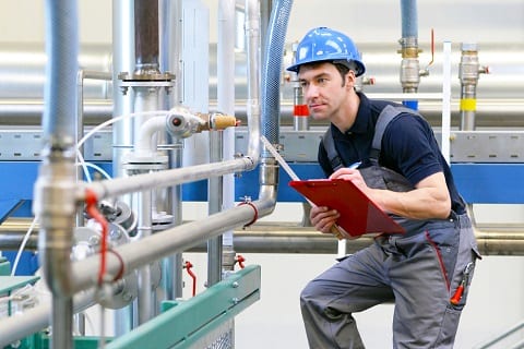 Maintenance technician performing preventive maintenance by inspecting machine with a checklist