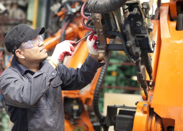 A young mechanic executing a work order for the repair of a robotic machine as part of the work order management process