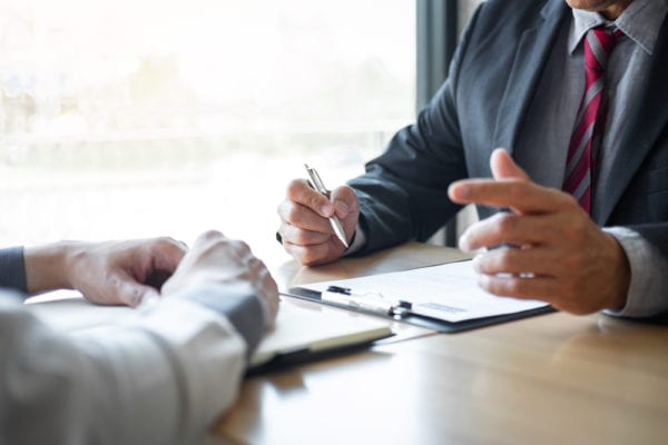 Executive in suit sitting at a table talking with another person about a proposal, representing CMMS stakeholders discussing a CMMS project