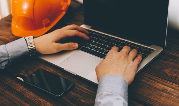 A maintenance professional searching for CMMS vendors on a laptop.