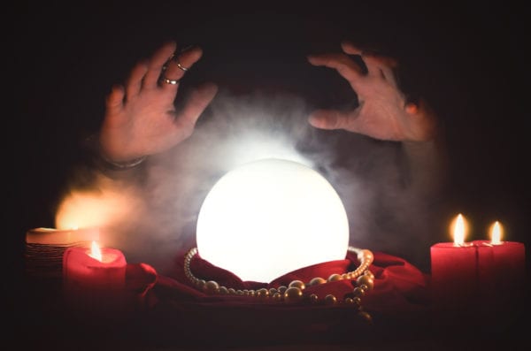 A fortune teller hovering her hands over an illuminated crystal ball attempting to predict maintenance needs.