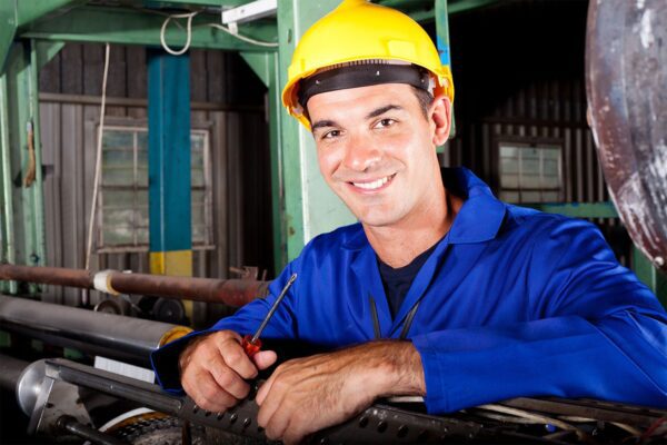 Young male technician repairing a printing machine, which will later by documented by a CMMS remedy code.