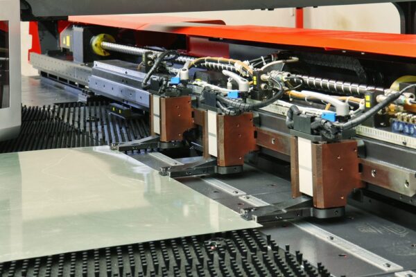 Close up of a CNC punching machine with a metal plate, part of a production line whose productivity is measured using overall equipment effectiveness.