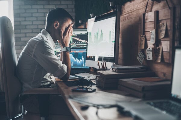 A worker at a computer with hands on face looking at report, wishing to replace his CMMS software.