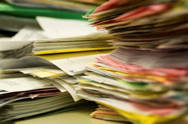 A paper work order management system represent by towering stacks of papers.