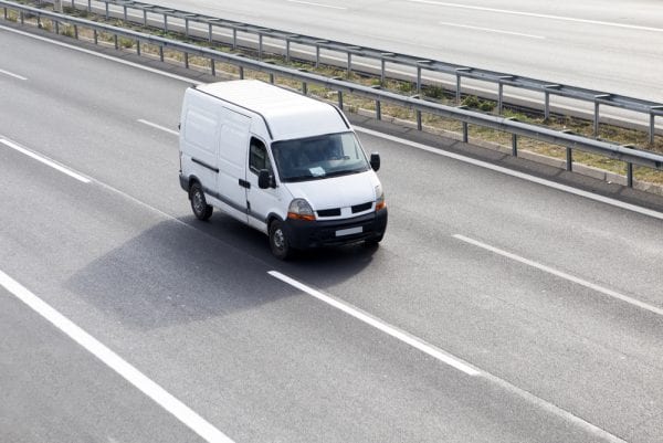 A sprinter van vehicle asset driving in the middle lane of a highway.