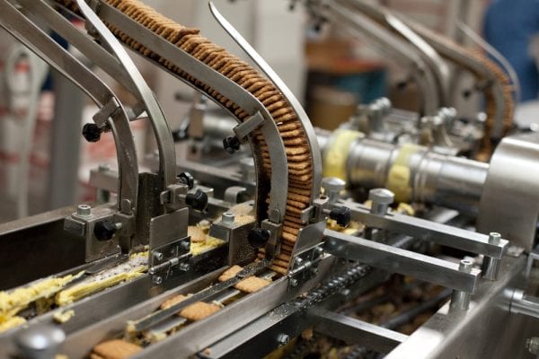 Crackers being fed into a conveyor system kept in peak condition through maintenance in the food industry.