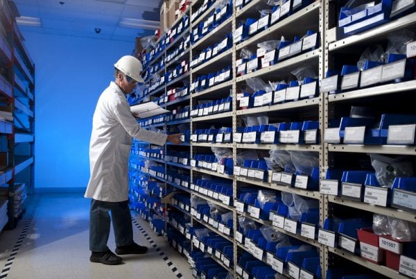 Maintenance worker checking inventory on a stockroom shelf to demonstrate the company’s inventory control techniques.