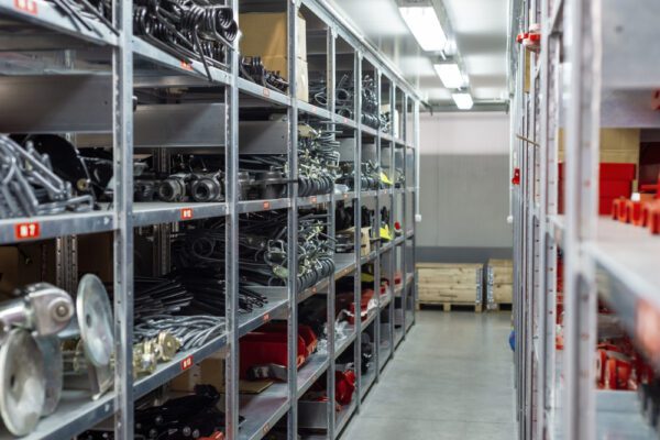 An organized maintenance storeroom showing large metal parts neatly organized on metal shelving in a clutter-free aisle.