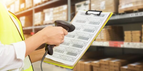 Stockroom worker scanning printed barcodes using a wired barcode scanner as part of a maintenance barcode system.