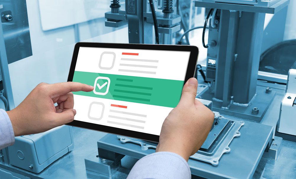 Person checking off tasks on a maintenance task checklist on a tablet computer in front of a machine