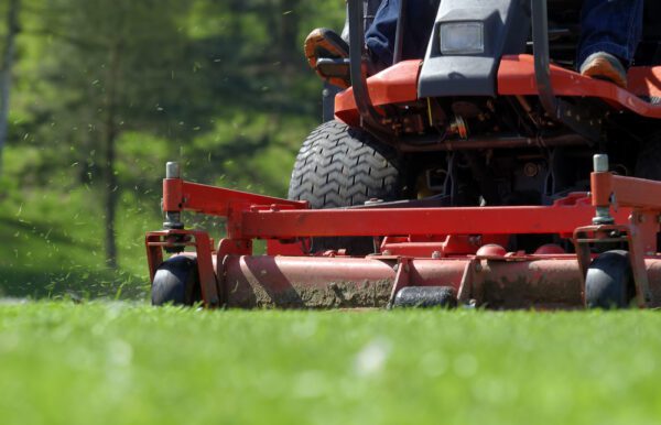 Close up of a riding lawn mower on a grassy field outside a building