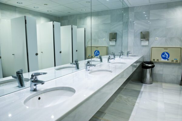 Modern, bright office restroom fixtures including sinks and toilet stalls
