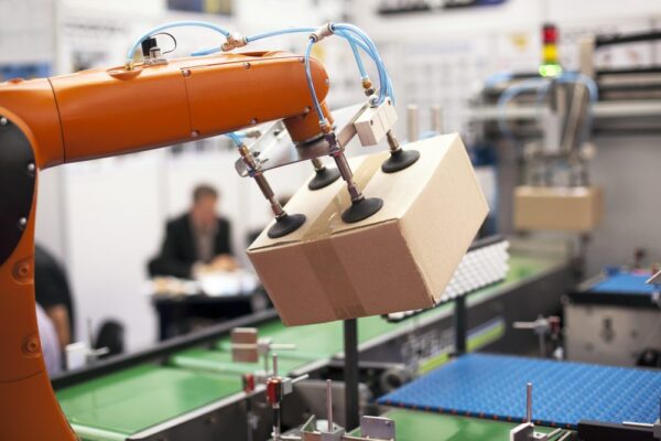 Manufacturing machine lifting a box with a robotic arm which has been maintained after the pandemic.