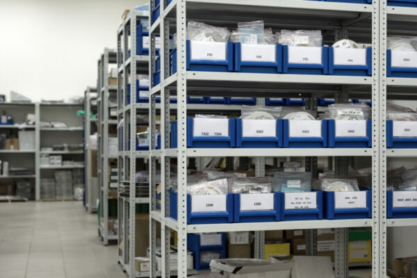 Spare parts inventory in blue bins on maintenance storeroom shelves.