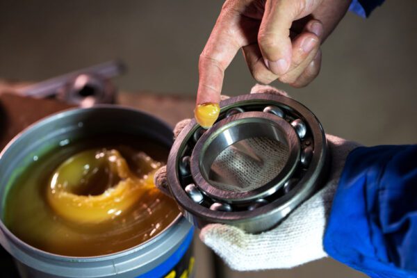 Technician’s hands applying lube to a bearing in line with preventive maintenance best practices.