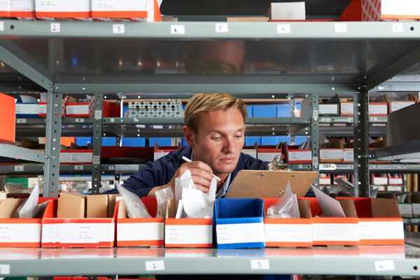 Male technician in a storeroom creating a purchase order based on stocking levels.