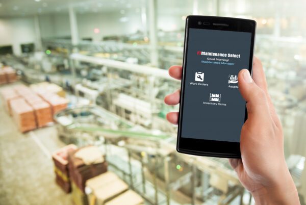 Person holding a smarthphone on a factory floor showing the FTMaintenance Select app