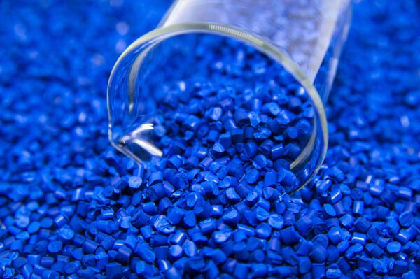 Blue plastic granules being measured in a glass measuring cup