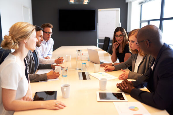 Group shot of young professionals in a board room discussing CMMS RFP vendor responses.