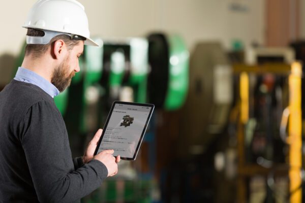 Close up of young male technician verifying a mobile CMMS performs its intended function during CMMS validation testing