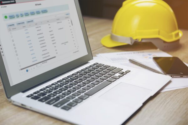 Close up of a laptop computer with FTMaintenance Select on a desk with a hard hat.
