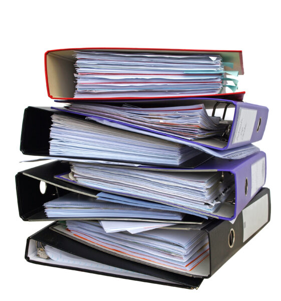 A stack of multiple binders representing documentation of an ISO 9001 compliant quality management system.