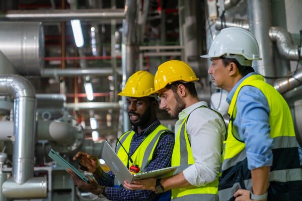 Medium shot of 3 maintenance technicians analyzing an issue with a pump system.
