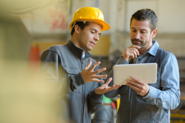 Young male technicians and supervisor looking at a tablet computer used to access on-premise CMMS software.