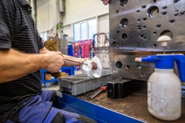 Close up of a an engineer cleaning an injection mold after production.