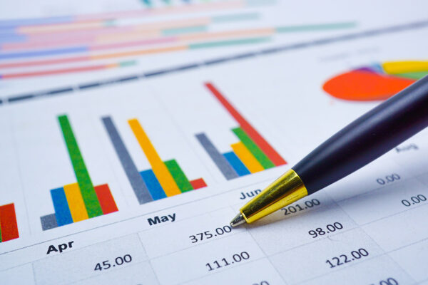 Close up of a pen pointing to a table of data with charts, indicating maintenance costs for the previous quarter.