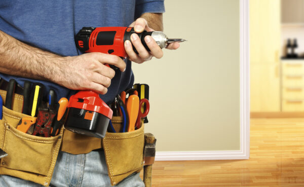 Medium close shot of a handyman in an apartment unit with a drill and tool belt