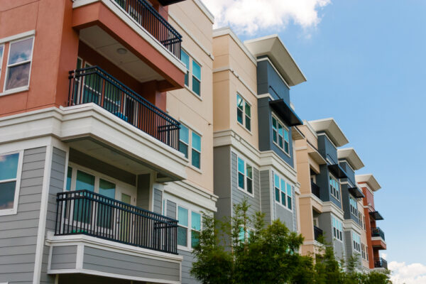Exterior shot of luxury apartments and tree tops with a blue sky