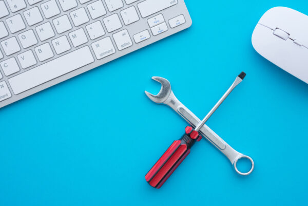 A wrench and screwdriver on a blue background with a computer keyboard and mouse.
