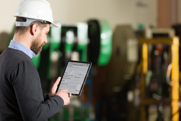 Young male engineer submitting a maintenance request using a request form on a tablet.
