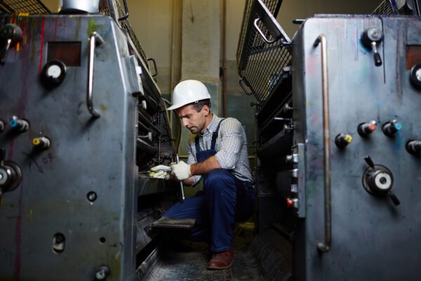 Young male technician repairing industrial equipment with hand tools.